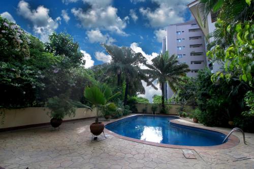 a swimming pool in a courtyard with trees and a building at La Cour Hotels and Apartments Glover in Lagos