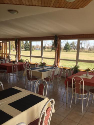 un comedor con mesas, sillas y ventanas en Tó Panzió Őrség Bajànsenye, en Bajánsenye