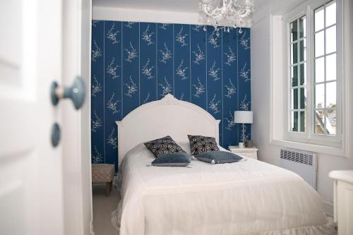 サン・ケ・ポルトリユーにあるVilla de villégiature pieds dans l'eauのベッドルーム1室(青い壁の白いベッド1台付)