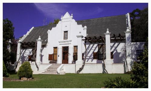 ein weißes Haus mit Treppen und einem Dach in der Unterkunft Mooiplaas Wine Estate in Stellenbosch