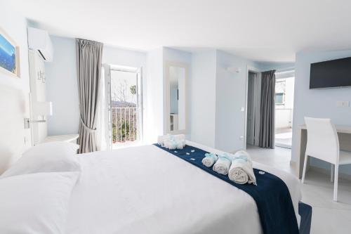 a white bedroom with a large bed with towels on it at Relais Kaora GUESTHOUSE in Sant'Agnello