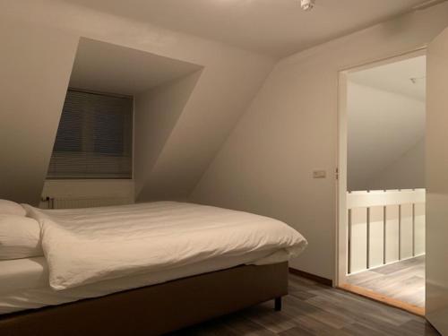 een slaapkamer met een bed en een raam op zolder bij Vakantie huisjes Duinrand Drunen in Drunen