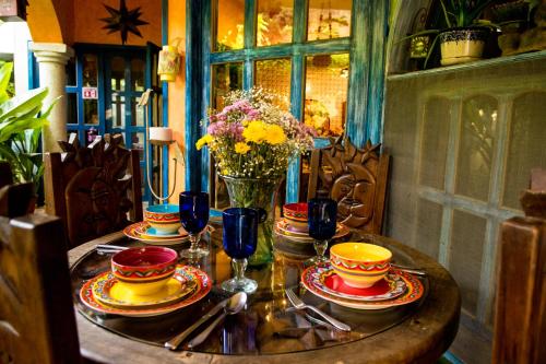 a table with plates and cups and a vase of flowers at Hacienda Boutique B&B and Spa Solo Adultos in Cozumel