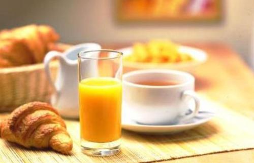 - un verre de jus d'orange à côté d'une tasse de café dans l'établissement La chambre des cht'is, à Vayrac