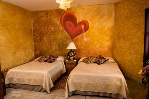 two beds in a room with a painting on the wall at Hacienda Boutique B&B and Spa Solo Adultos in Cozumel