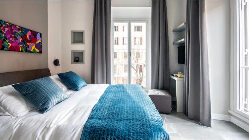 - une chambre avec un lit doté d'oreillers bleus et d'une fenêtre dans l'établissement Moma Roma, à Rome