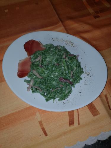 a white plate of greens on a wooden table at El Rocol in Vezza dʼOglio