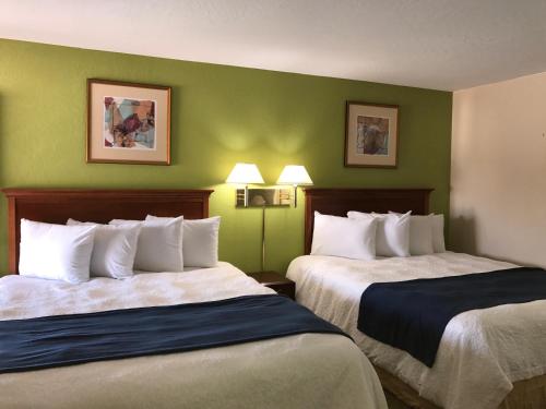 two beds in a hotel room with green walls at Red Bluff Inn in Red Bluff