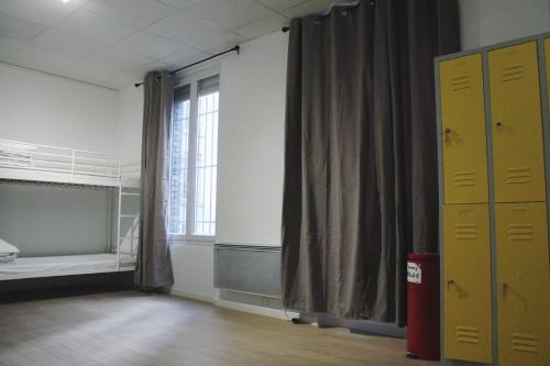 an empty room with a bed and a window at Le Coffice Auberge de Jeunesse in Paris
