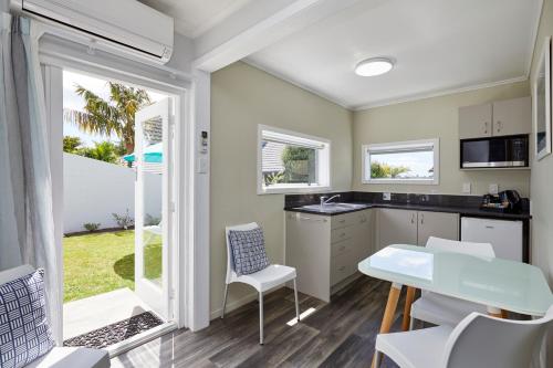 a kitchen with white cabinets and a table and chairs at Harbour View Motel and Waterfront Apartments in Tauranga