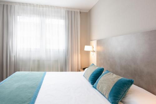 a bedroom with a bed with blue pillows and a window at Hotel & Spa Real Jaca in Jaca