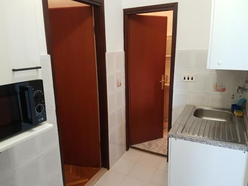 a kitchen with a door and a sink and a microwave at Apartments Zova in Medulin