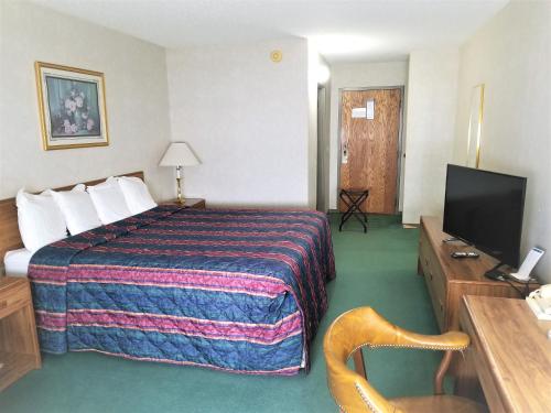 a hotel room with a bed and a flat screen tv at Abby Inn in Abbotsford