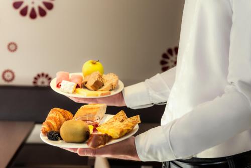a chef is holding two plates of food at ibis Massy in Massy