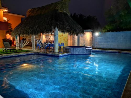 a swimming pool at night with a thatched umbrella at Chalet en Puerto San Jose in San José de Guatemala