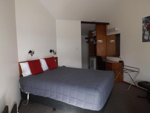 1 dormitorio con 1 cama con almohadas rojas y blancas en Gateway Motor Lodge - Wanganui, en Whanganui