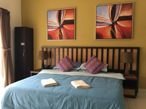 um quarto com uma cama azul com duas toalhas em Happy Stay @ Morib Gold Coast em Banting