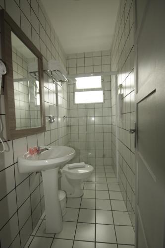 a white bathroom with a sink and a toilet at Kennedy Slim Hotel in São José