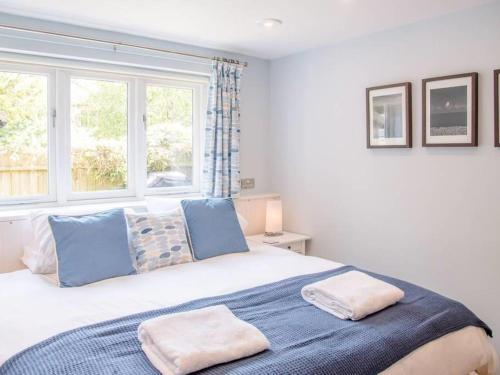 a bedroom with a large bed with blue pillows and a window at Suilven Holiday Let in Aldeburgh
