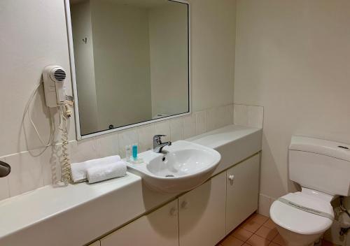 a bathroom with a sink and a toilet and a mirror at Outrigger Burleigh in Gold Coast