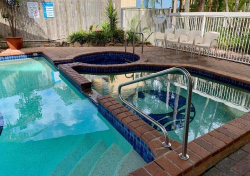 a swimming pool with a stairway leading to a patio with chairs at Outrigger Burleigh in Gold Coast