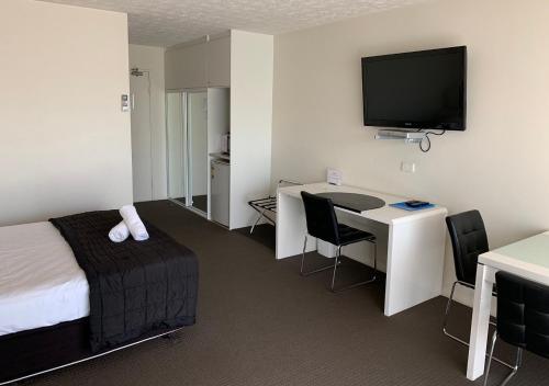 a hotel room with a bed and a desk with a television at Outrigger Burleigh in Gold Coast