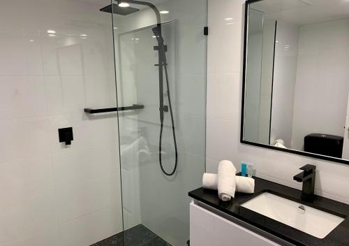 a bathroom with a shower with a sink and a mirror at Outrigger Burleigh in Gold Coast