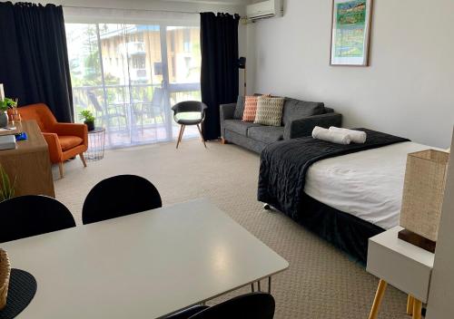a bedroom with a bed and a couch and a table at Outrigger Burleigh in Gold Coast