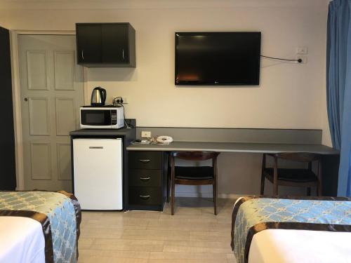 a hotel room with a desk with a microwave and a tv at Oxley Motor Inn in Brisbane