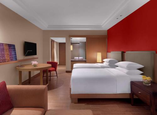 a bedroom with a large white bed and a red wall at Hyatt Regency Kuantan Resort in Kuantan
