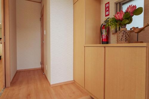 a hallway with a cabinet with flowers in it at Hyakuna Terrace in Nanjo