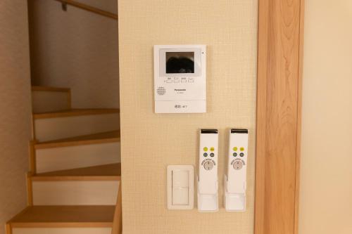 a wall with a thermometer and a clock on a wall at Hyakuna Terrace in Nanjo