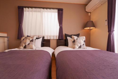 two beds in a room with a window at Hyakuna Terrace in Nanjo