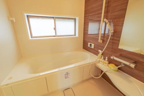 a bathroom with a tub and a window at Hyakuna Terrace in Nanjo