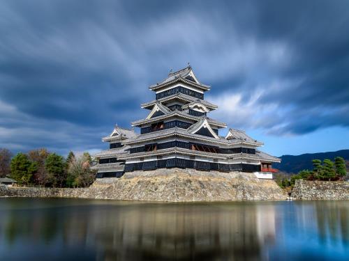 a large building sitting on top of a body of water at Yumotoya in Matsumoto