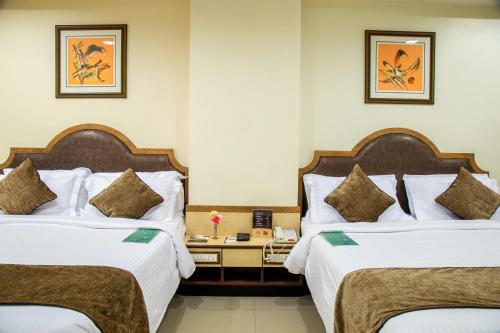 una camera d'albergo con due letti e un tavolo di Hotel Tip Top Plaza a Thane
