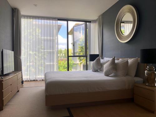 a bedroom with a large bed and a mirror at Baan Mai Khao in Mai Khao Beach