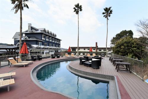 a resort pool with lounge chairs and palm trees at Alaise De Bale Shirahama in Shirahama