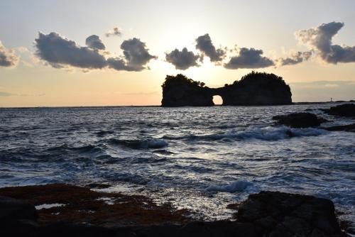 a sunset over the ocean with a rock in the water at Alaise De Bale Shirahama in Shirahama