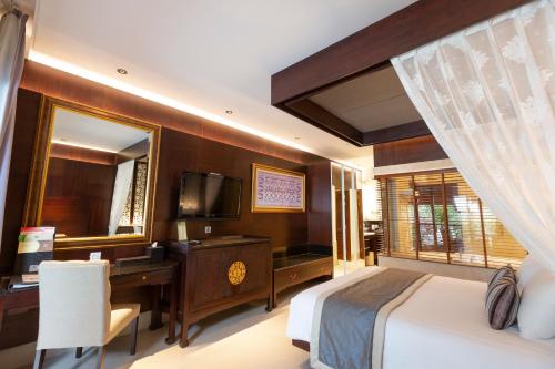 a bedroom with a bed and a desk and a television at Puri Santrian Beach Resort And Spa in Sanur