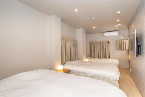 two beds in a room with white sheets at Kyoto Takatsuji Rose Heights in Kyoto