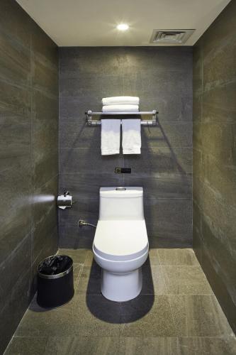 a bathroom with a toilet with towels and a trash can at INSAIL Hotel (Shenzhen Dongmen Branch) in Shenzhen