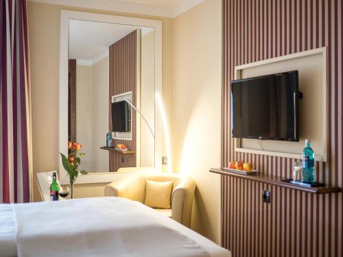 a hotel room with a bed and a flat screen tv at Hotel Primula in Troisdorf