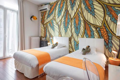 two beds in a room with a colorful wall at Hôtel Cecil - Boutique hôtel in Juan-les-Pins