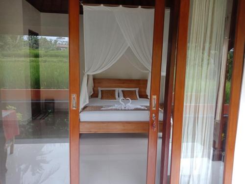 a bed in a room with a glass door at Ubud Sawah Scenery Villa and Homestay in Tegalalang