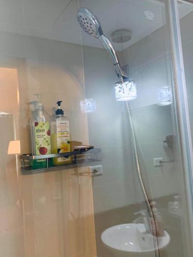 a shower in a bathroom with a sink at H&M One Palmtree Villas in Manila