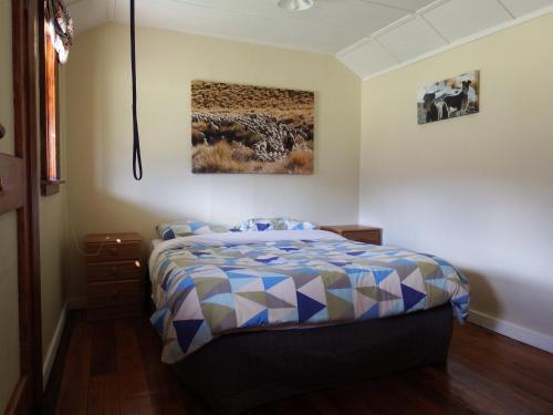 奧瑪拉瑪的住宿－鄧斯坦唐斯高地鄉村羊場農家樂，卧室配有一张床,墙上挂有绘画作品