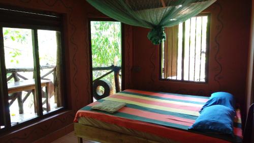 a bedroom with a bed and two windows at Beach Hut in Arugam Bay