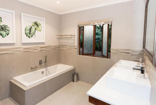 a bathroom with a bath tub and a sink at Kruger Park Lodge Unit No. 612 in Hazyview