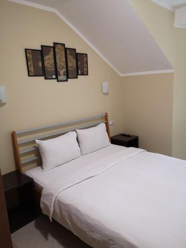 a bedroom with a white bed with three pictures on the wall at Villa i SPA Stević in Veliko Gradište